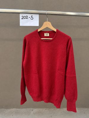 Le pull rouge est suspendu à un cintre devant un mur.