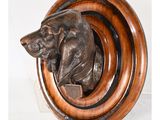 une image représentant une tête de chien en bronze fixée sur une plaque en bois