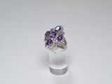 un gros plan d'une bague ornée de pierres violettes sur un fond blanc
