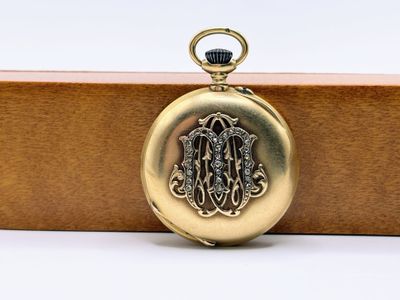un gros plan d'une montre de poche en or posée sur une boîte en bois