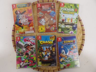 Plusieurs jeux vidéo sont disposés dans un panier en osier posé sur une table