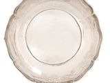 an antique silver plate with a scalloped edge on a white background
