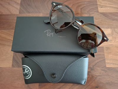 une paire de lunettes de soleil posée sur un étui noir, sur un plancher en bois