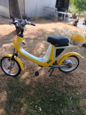 a small yellow and white scooter parked in the grass