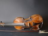 an old violin sits on a black surface next to a bow