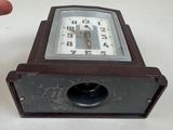 a small clock sitting on a table next to a hand