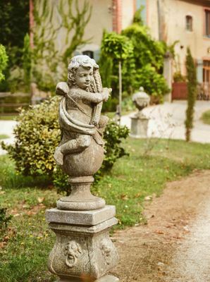 une statue d'ange posée sur un socle devant une maison