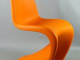 une chaise orange posée sur une surface blanche