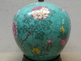 un vase vert avec des fleurs posé sur une table