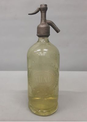 une bouteille en verre à l'ancienne, munie d'un bec verseur en métal, posée sur une surface blanche