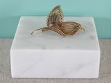 a white marble box with a gold leaf on top