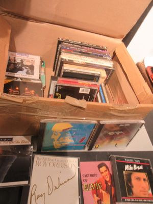 une boîte remplie de CD et des CD posés sur une table