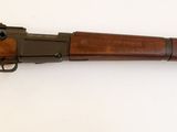 un vieux fusil posé sur une surface blanche, muni d'une crosse en bois