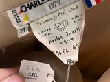the label on the back of a beige jacket is attached to a person ' s pants
