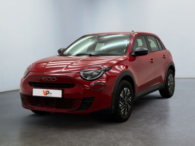Une voiture rouge est garée dans une pièce aux murs blancs.