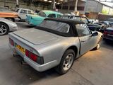 a silver sports car parked in a garage with other cars