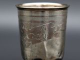 une vieille coupe en argent posée sur une table, sur laquelle figure un monogramme