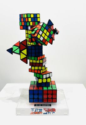 a multicolored rubik cube sculpture on a clear base