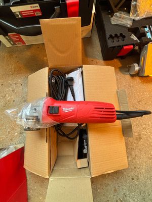 une perceuse filaire rouge dans une boîte en carton posée par terre