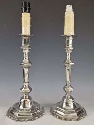 pair of silver candlesticks with candles on each of them