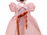 un gros plan d'une poupée portant une robe rose et un bonnet
