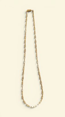 collier avec une chaîne en or et des perles sur fond blanc