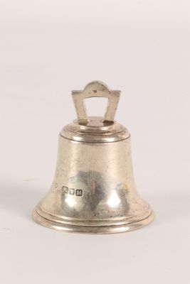 an old silver bell on a white surface with a white background