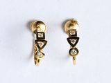 une paire de boucles d'oreilles en or et diamants posées sur un fond blanc