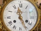 a gold clock with roman numerals on the face of it