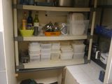 a small kitchen with a lot of clutter on the shelves