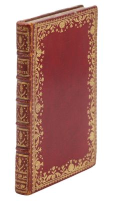 un vieux livre à la couverture rouge posé sur une surface blanche