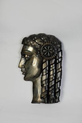 une sculpture métallique représentant la tête d'une femme sur fond blanc