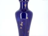 un vase bleu orné d'étoiles dorées, posé sur un fond blanc