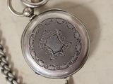 a silver pocket watch with a chain around it