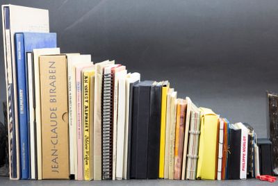 a black cat sitting next to a stack of books