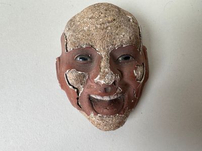 un masque en argile accroché au mur d'une pièce