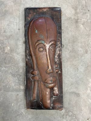 une plaque métallique représentant un visage, accrochée au mur