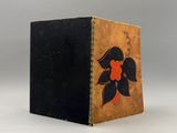 un vieux livre à la couverture noire ornée d'une fleur rouge