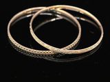 a pair of gold hoop earrings on a black surface