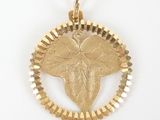 a close up of a gold pendant with a leaf on it