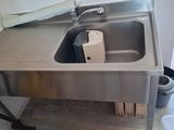 a stainless steel sink and a trash can in the kitchen