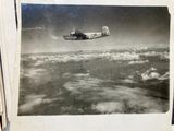 a black and white photo of a plane flying above the clouds