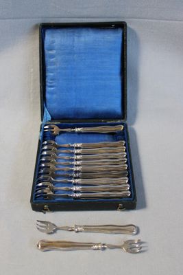 des couverts dans un coffret bleu posé sur une nappe blanche