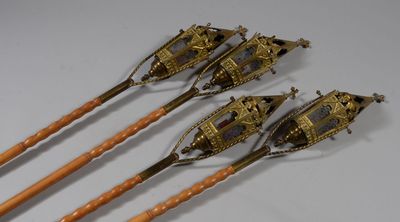 three antique brass spoons with wooden handles on a white surface