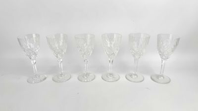 six verres à vin transparents alignés sur une surface blanche