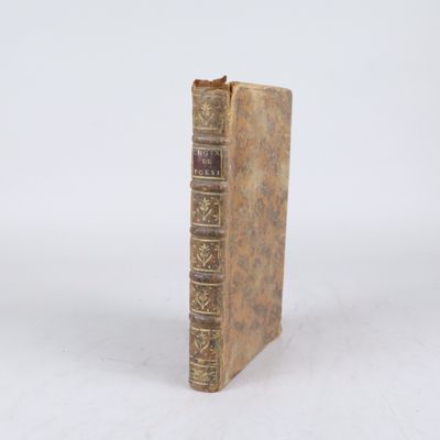 un vieux livre posé sur une table blanche à côté d'un mur blanc