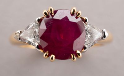 a close up of a ring with a red stone surrounded by white diamonds