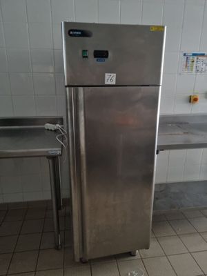 un réfrigérateur en acier inoxydable dans une cuisine, avec une table en arrière-plan