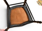 a person that is holding a chair that has a cushion on it