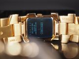 a gold wrist watch with a blue face on a table